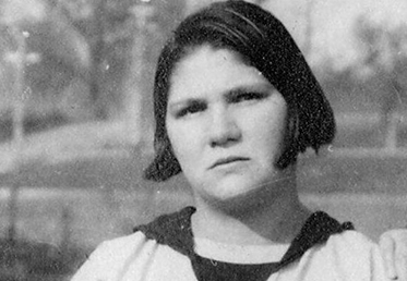 A young woman with pale skin and dark hair looking pensive.